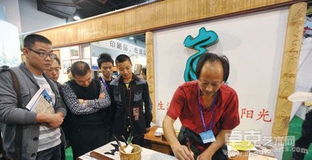 陈志炎在杭州文博会富阳展区前现场书法，挂在“门楣”上的就是他的竹雕作品《富春山居图》。